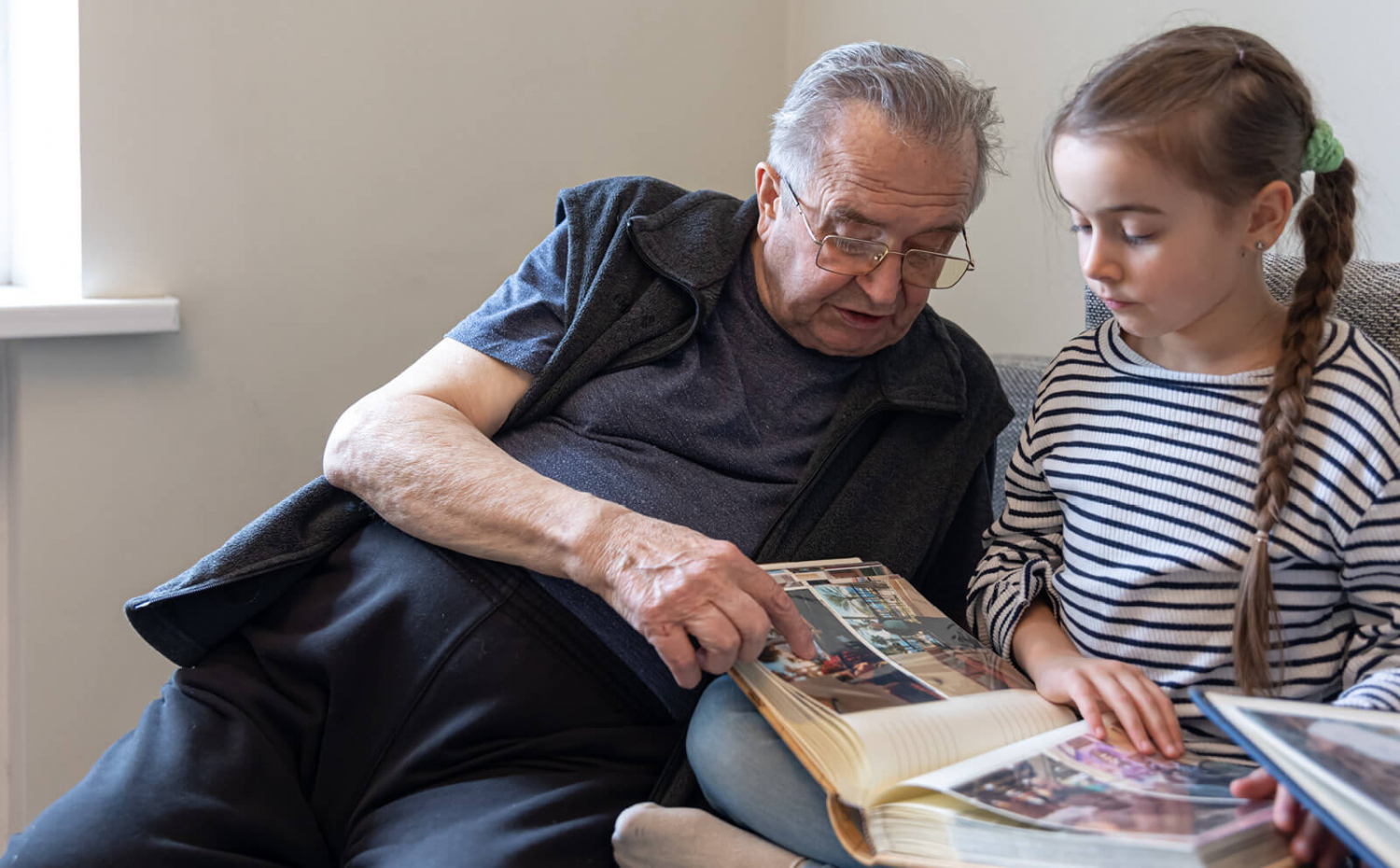 A grandfather showing his granddaughter a photo album.